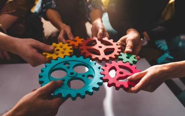 colorful gears being held by teammates in a circle